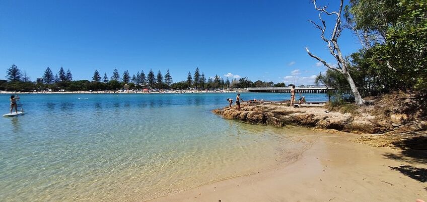 People swimming and paddleboarding at Echo Beach, one of the scenic attractions around Gold Coast with calm waters and sandy shores.