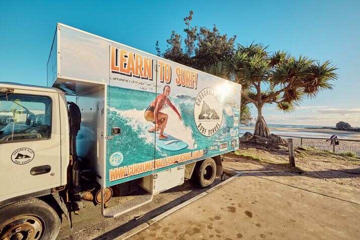 currumbin surf school truck at currumbin alley, beachside learn-to-surf setup with ocean in the background